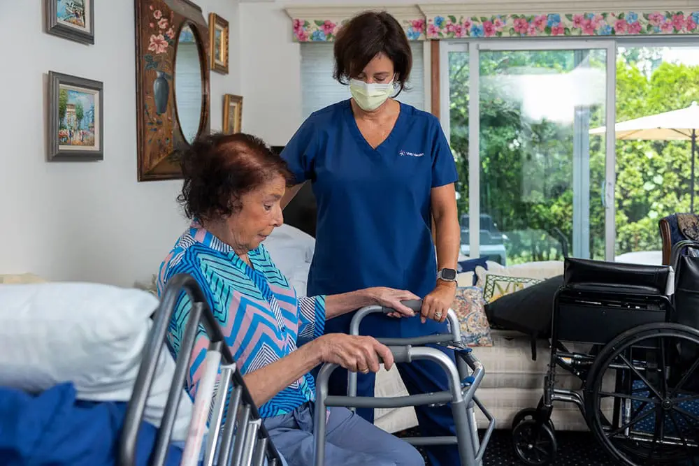 Caregiver steadying an older adult using a walker at home