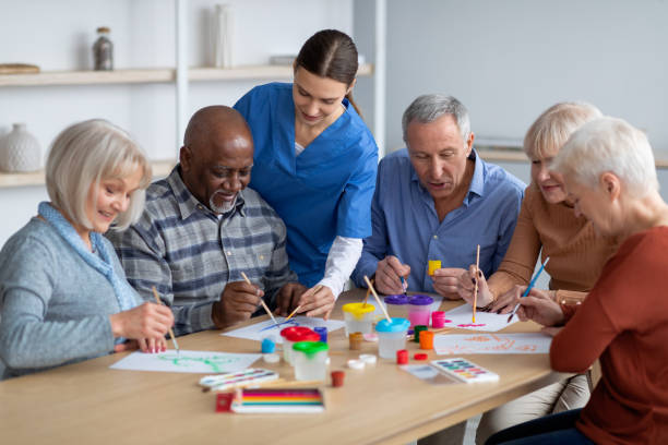 Caregiver guiding a group of older adults through a painting activity