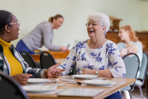 Older woman laughing with a companion at a shared lunch table